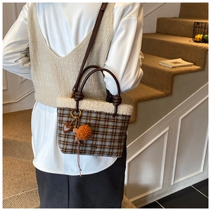 Detail of plaid wool tote bag with white faux fur trim and brown leather handle