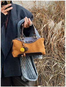 Détail du nœud en daim et pompon coloré sur un sac à main vintage marron