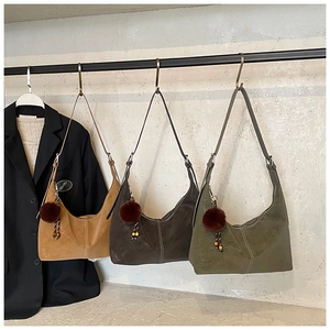 Detailed view of suede hobo bags in brown and olive with pompom and contrast stitching