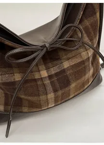 Close-up of vintage check wool tote bag featuring a leather bow and zip closure