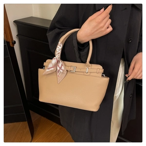 Detailed view of apricot textured leather tote with silk scarf handle and belt buckle detail