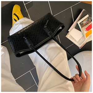 Détail du sac bandoulière en cuir tressé noir avec nœud décoratif sur la bandoulière