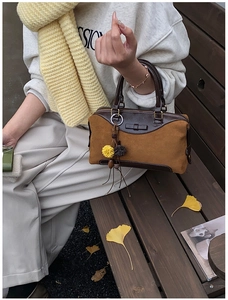 Détail du sac Boston vintage en daim marron avec garniture en cuir et breloque florale