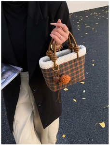 Detail of plaid handbag with faux fur trim and decorative heart charm in outdoor setting