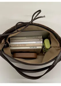 Macro view of large brown tote bag showing spacious interior with laptop and books