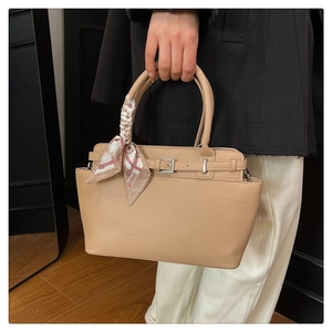 Detail of beige textured leather handbag with silver buckle and printed silk scarf handle