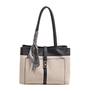 Beige canvas tote bag with black leather trim, gold twist lock, and a patterned scarf accessory