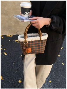Detailed view of checkered wool tote bag with white faux fur trim and leather handles