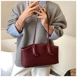 Détail macro du cuir tressé bordeaux et de la bandoulière nouée du sac à main pour femme