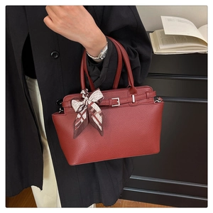 Close-up of reddish-brown pebble leather handbag with silk scarf wrap and silver buckle