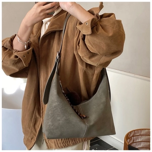 Detailed view of the large grey-green suede hobo bag with a polka dot woven zipper pull
