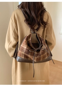Detail of retro plaid tote bag featuring brown leather trim and drawstring closure