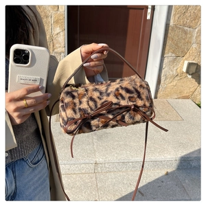 Detail of leopard print plush barrel bag featuring brown leather bows and slim strap