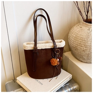 Detailed texture of brown suede bucket bag with white faux shearling trim and plush pompom