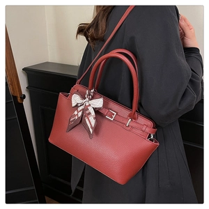 Detail of brick red lychee texture handbag with silk scarf bow and silver hardware