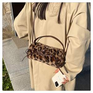 Detail of leopard print faux fur cylinder bag featuring a leather bow and slim shoulder strap