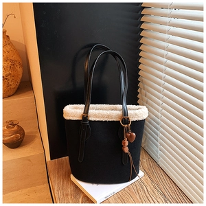 Detail of black suede bucket bag with faux shearling trim and stylish heart charm