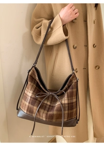 Detail of retro brown checkered hobo bag with leather trim and bow on a model