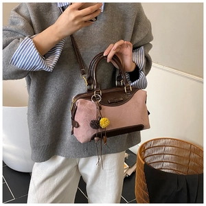 Détail du sac à main en daim rose avec finitions en cuir marron et pendentif pompon