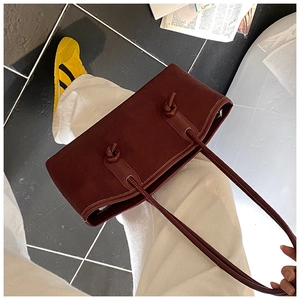 Détail du sac cabas bordeaux avec texture gaufrée et élégant nœud sur la poignée