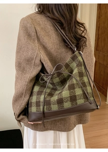 Detail of green and brown checkered tote bag with drawstring bow and leather trim