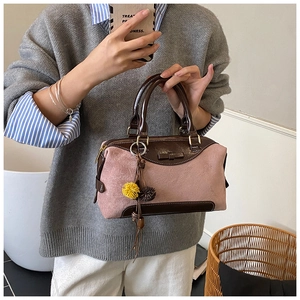 Détail du sac à main Boston en daim rose et cuir marron avec breloque pompon doux