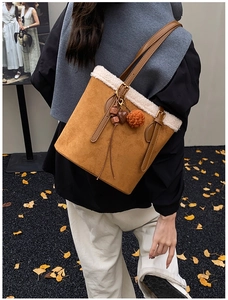 Detail of suede tote bag with white faux shearling trim and colorful leather pendants