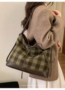 Close-up of green checkered woolen tote bag with leather bow and shoulder strap detail