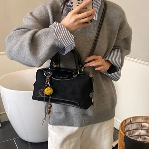 Détail du sac noir à nœud avec textures en daim et breloque fleurie sur la bandoulière