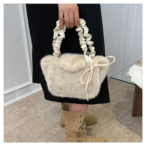 Detail of plush cream handbag featuring ruched cloud handle and ribbon bow accents