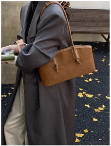Détail d'un sac à bandoulière en cuir tressé marron avec des accents de nœuds décoratifs