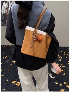 Close-up of caramel suede tote bag with faux shearling trim and decorative heart charm