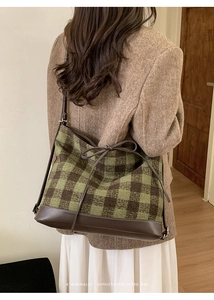 Macro detail of the green checkered tote bag showing woven texture and leather drawstring bow