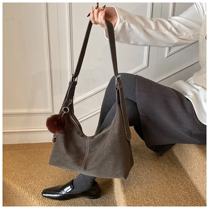 Hobo shoulder bag in dark suede with white stitching and plush ball charm detail