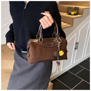 Détail d'un sac à main marron vintage avec nœud et breloques à pompons et franges