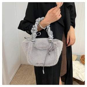 Detail of grey faux fur handbag with satin pleated handle and delicate bow decorative element