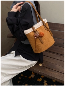 Outdoor shot of brown suede bucket bag with white fleece trim and heart-shaped pendant detail