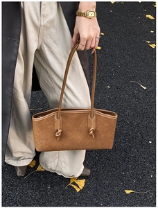 Détail de sac en cuir tressé marron avec nœuds décoratifs dans un décor d'automne