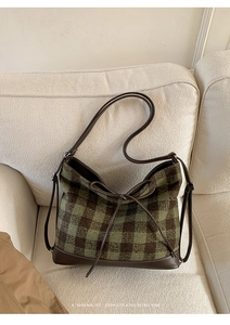 Detail of green plaid tote bag with brown leather base and delicate bow decoration