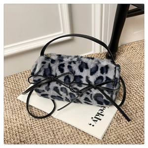 Detailed view of leopard print plush handbag with black bow and gold zipper on magazine