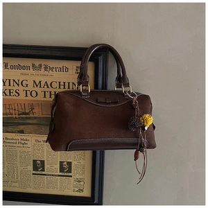 Détail du sac à main vintage marron foncé avec texture daim et pendentif à pompon