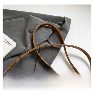 Détail d'une bandoulière en cuir marron confortable sur un sac vintage tissé