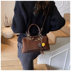 Sac bandoulière marron avec nœud et pompon porté dans le dos par un mannequin