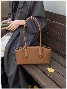 Gros plan sur un sac fourre-tout en cuir tressé marron avec motif à damier et nœud