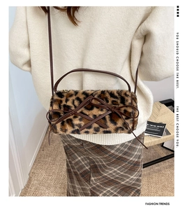 Detail of leopard print plush bag with bow accents and slim leather shoulder strap