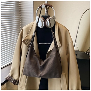 Detail of brown faux suede shoulder bag featuring contrast white stitching on matte texture