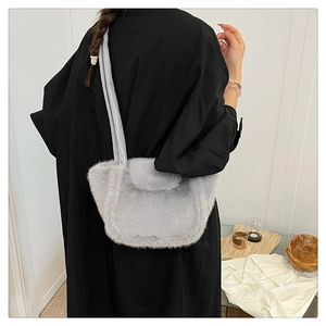 Detail of light gray faux fur handbag worn as an underarm shoulder bag on model