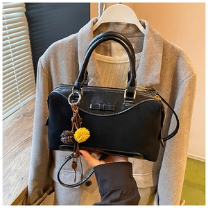 Gros plan du sac noir avec nœud en cuir et breloque pompon bicolore élégante