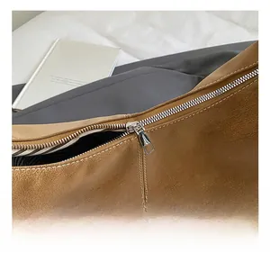 Detail of silver zipper closure and striped lining on brown suede shoulder bag