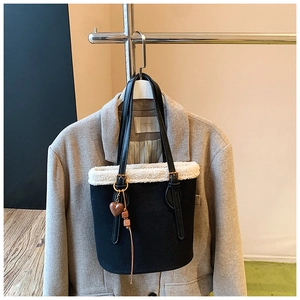 Detail of black suede tote with white faux shearling trim and heart pendant